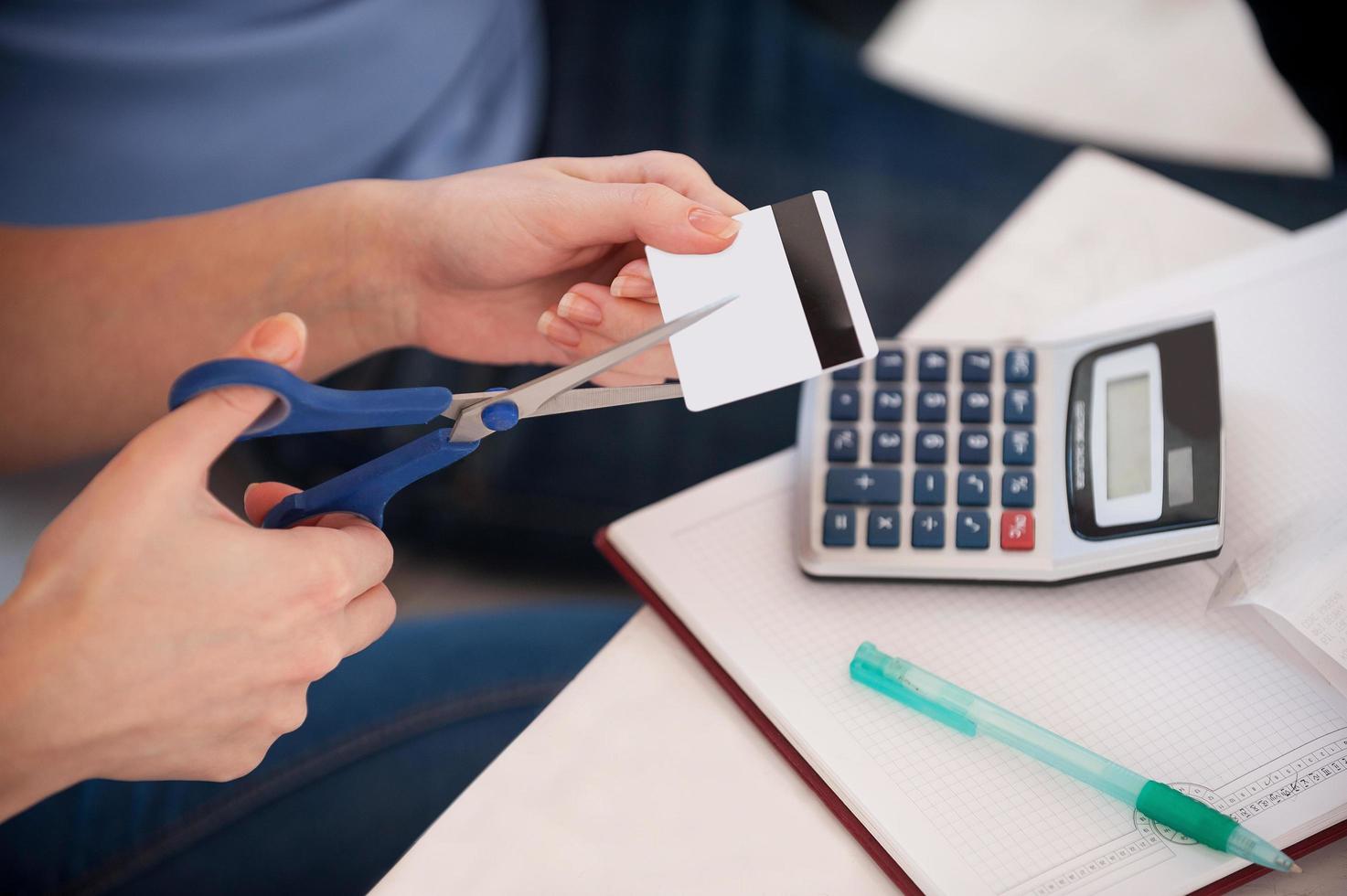 recortando los gastos. imagen recortada de una mujer cortando una tarjeta de crédito con unas tijeras foto
