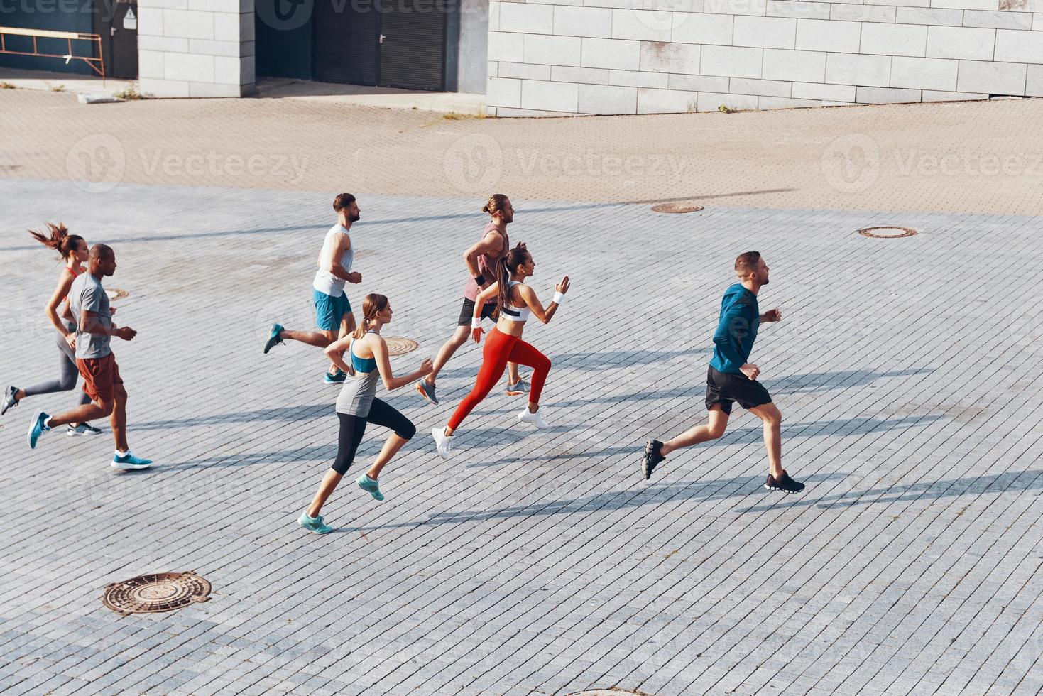 Full length top view of young people in sports clothing jogging while exercising outdoors photo