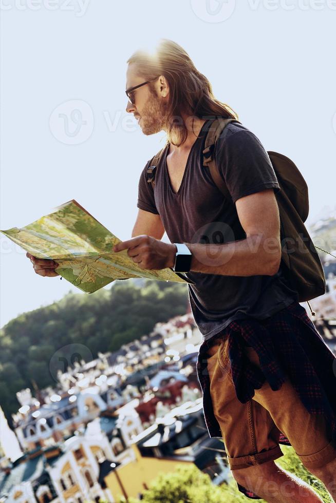 Freedom. Handsome young man in casual clothing holding map and looking away while standing on the hill outdoors photo