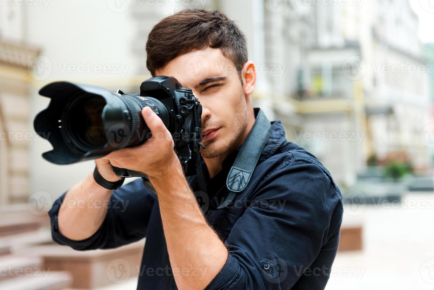 listo para disparar joven seguro de sí mismo fotografiando algo mientras está de pie al aire libre foto