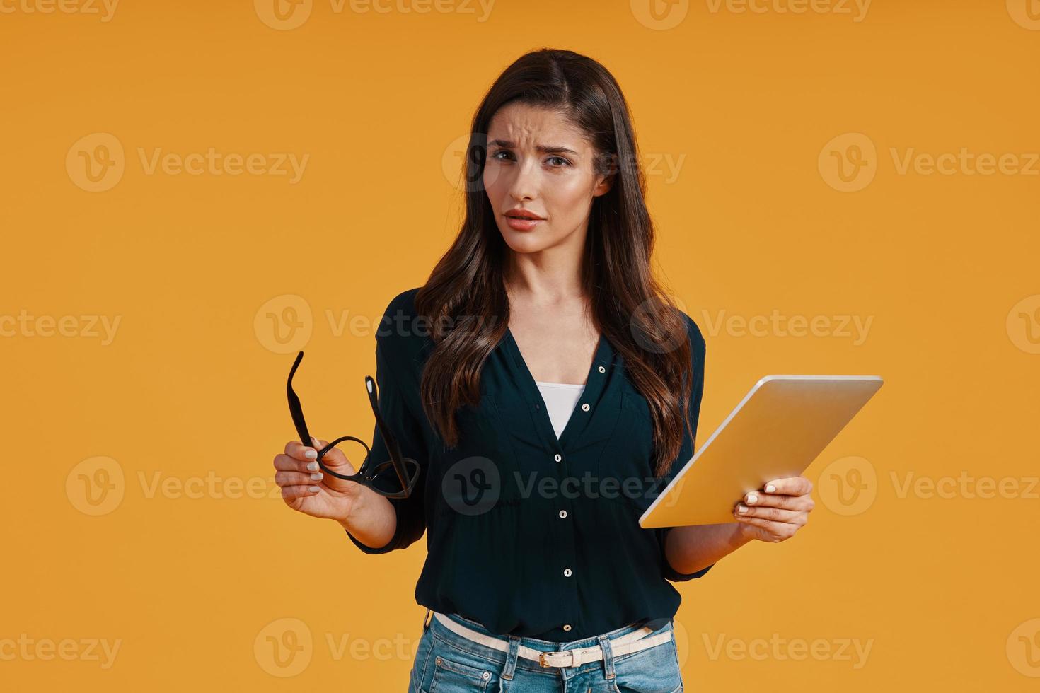 Confident young woman in smart casual clothing using digital tablet and looking at camera photo