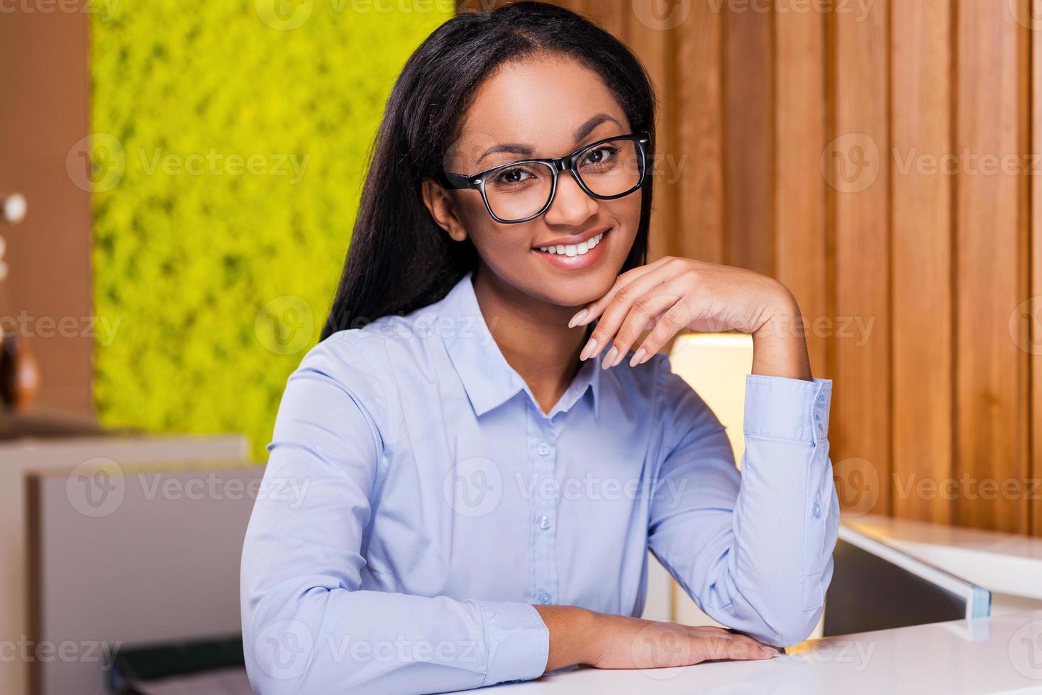 Making business look good. Attractive young African woman looking at you and smiling while standing at the reception photo