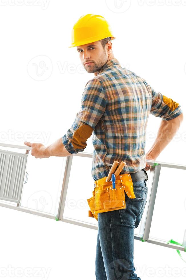 Handyman at work. Confident young repairman carrying ladder and looking at camera photo