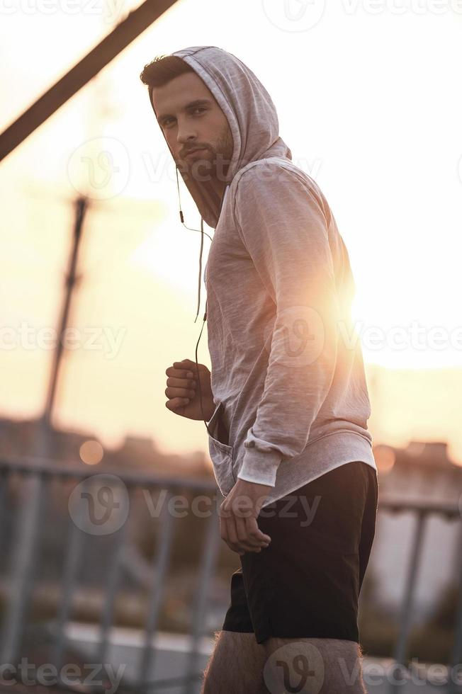 listo para correr. vista de ángulo bajo de un joven con ropa deportiva mirando la cámara mientras se prepara para correr foto