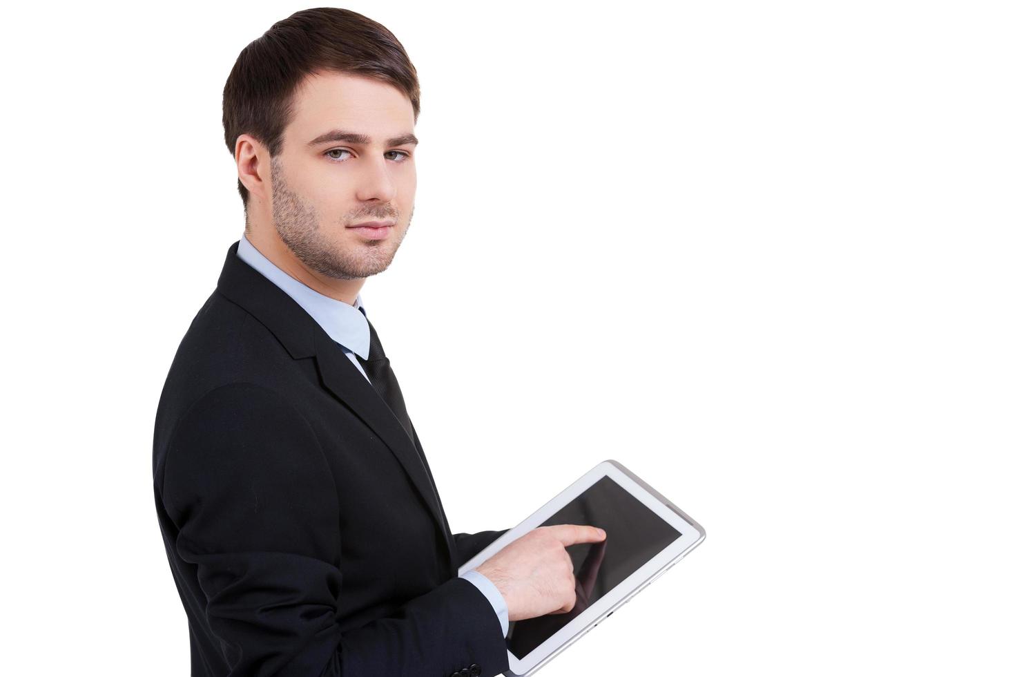 Businessman from digital age. Confident young man in formalwear working on digital tablet and looking at camera while standing isolated on white photo