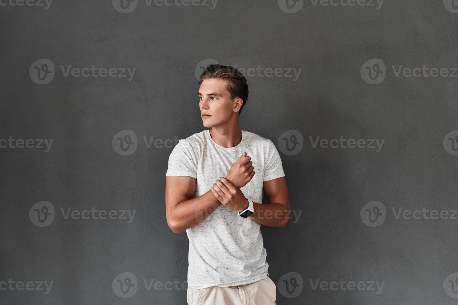 Used to look perfect. Handsome young man looking away while standing against grey background photo