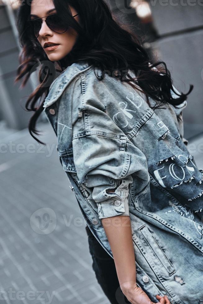 Attractive young woman looking over her shoulder while walking down the street photo