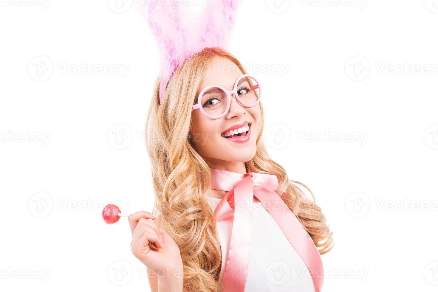 Easter bunny with lollipop. Beautiful young blond hair woman with rabbit ears holding lollipop and smiling while standing isolated on white background photo