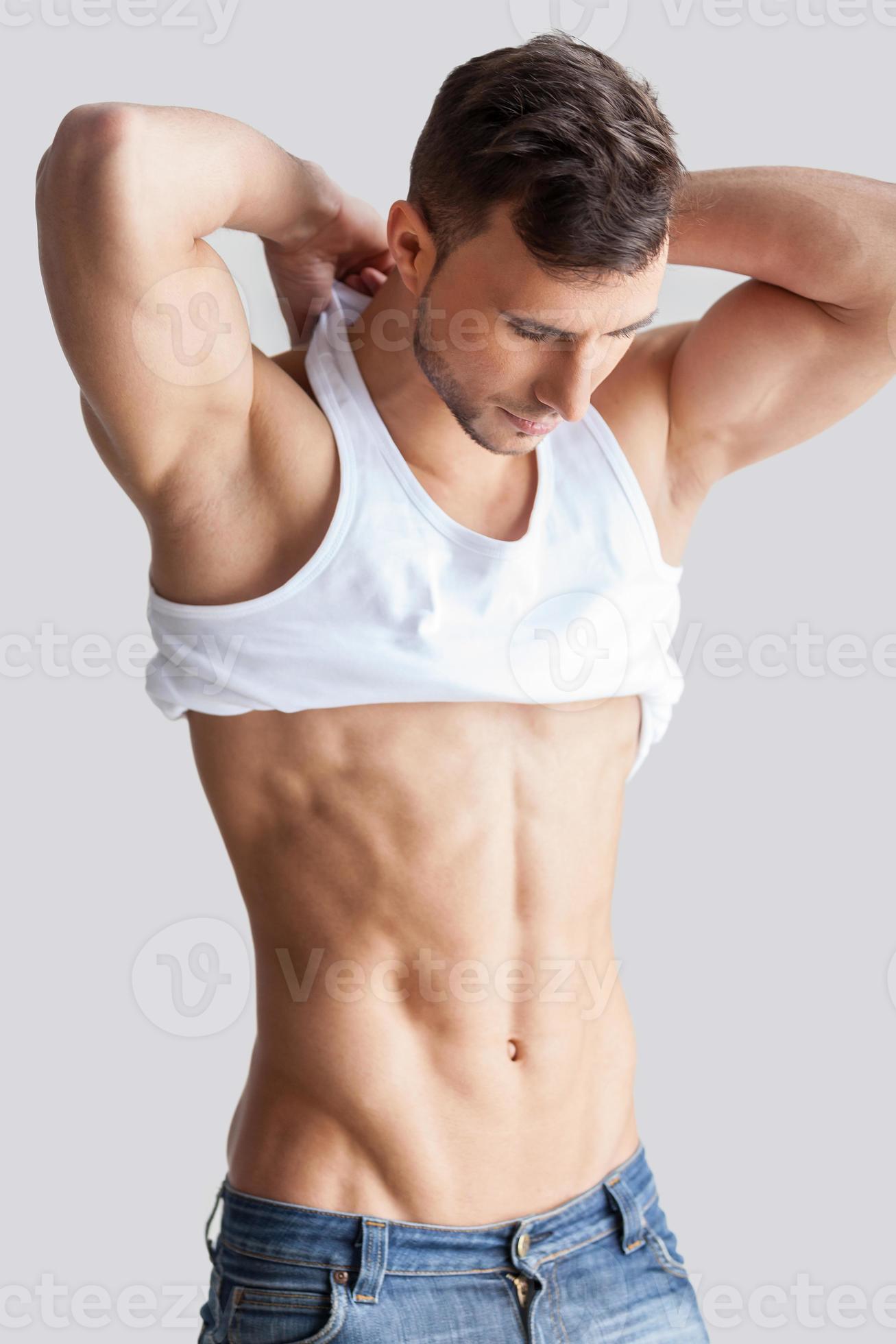 Man undressing. Handsome young muscular man taking off his tank