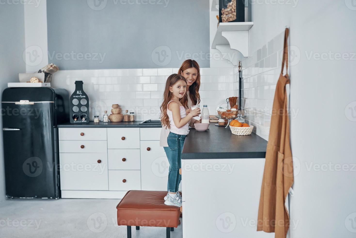 Mother and daughter smiling while preparing something at the kitchen photo