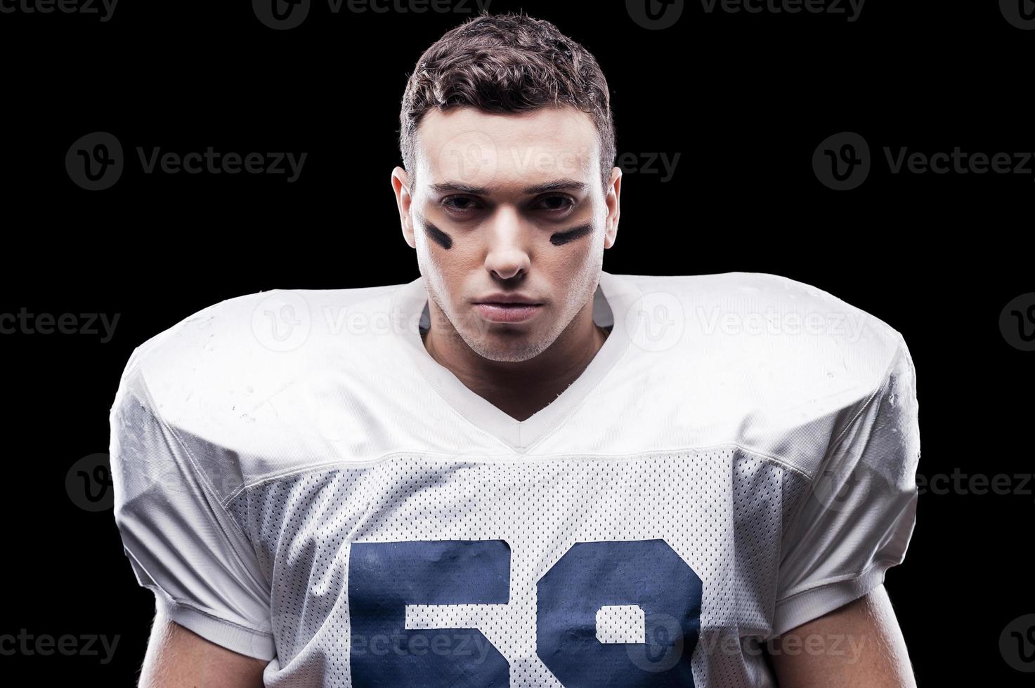 A real fighter.  American football player looking at camera while standing against black background photo