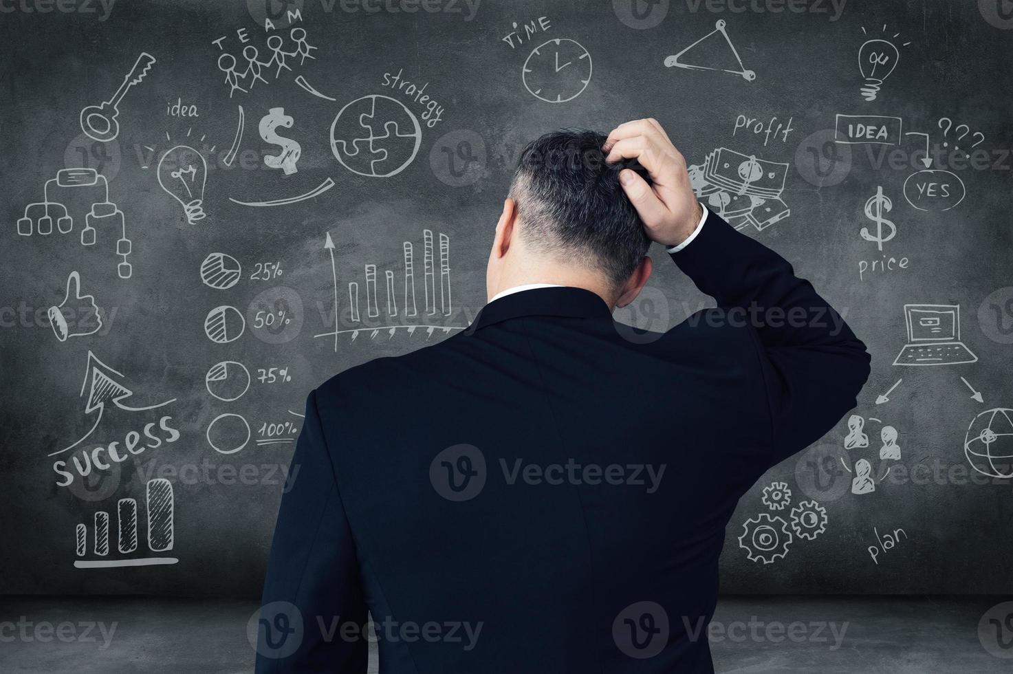 Which way shall I choose Rear view of pensive mature man scratching his head and looking at digitally composed business signs and charts on chalkboard photo