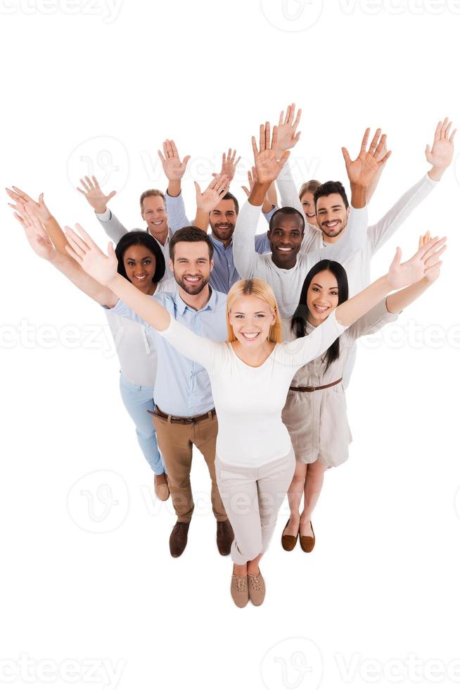 Dream team. Top view of positive diverse group of people in smart casual wear looking at camera and stretching out their hands while standing close to each other photo