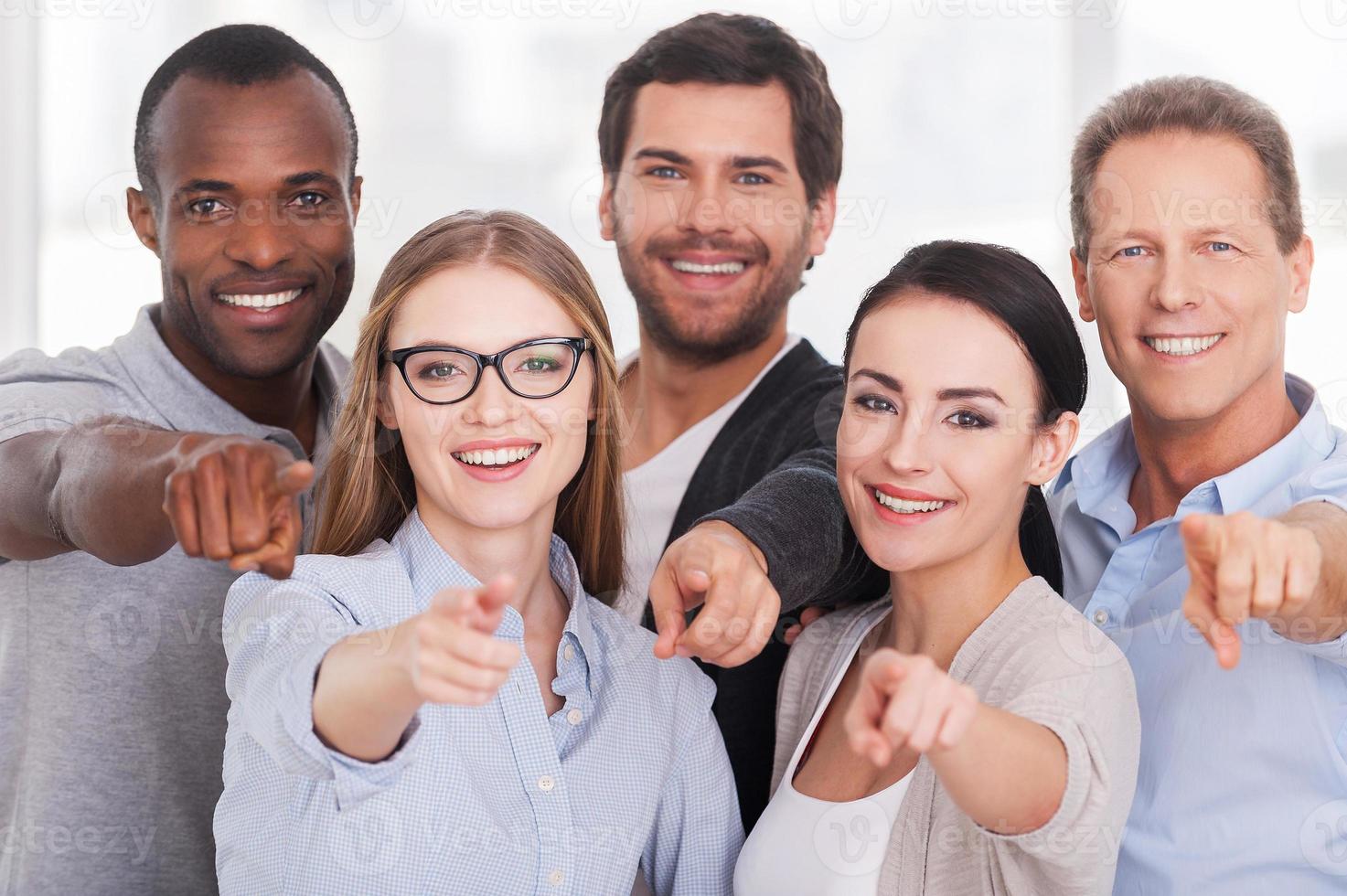 elegimos a su grupo de gente de negocios alegre con ropa informal parados uno cerca del otro y señalándolo foto