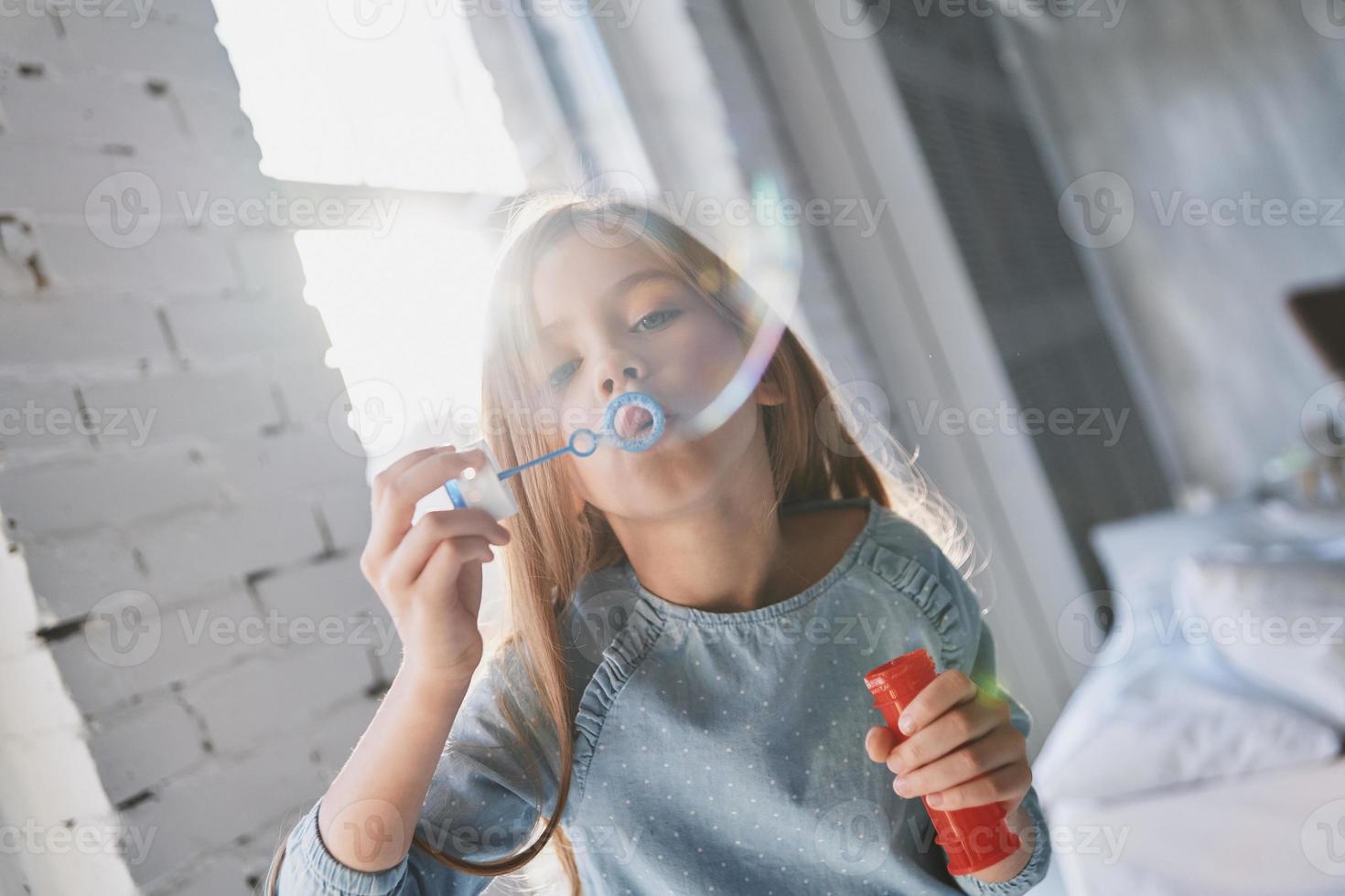 Cute little girl blowing a soap bubble while spending time at home photo