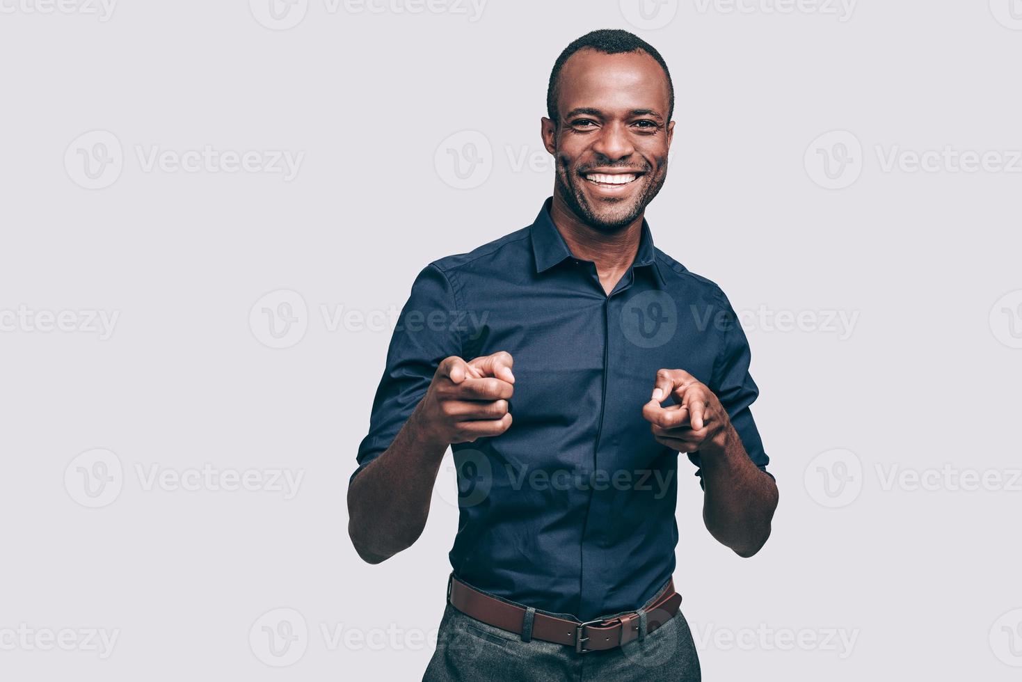 Choosing you. Handsome young African man pointing you and smiling while