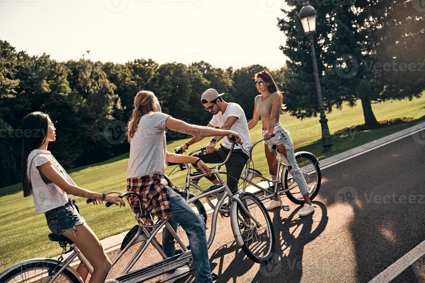 Gran día para un paseo en bicicleta. grupo de jóvenes modernos en ropa casual en bicicleta mientras pasan tiempo sin preocupaciones al aire libre foto