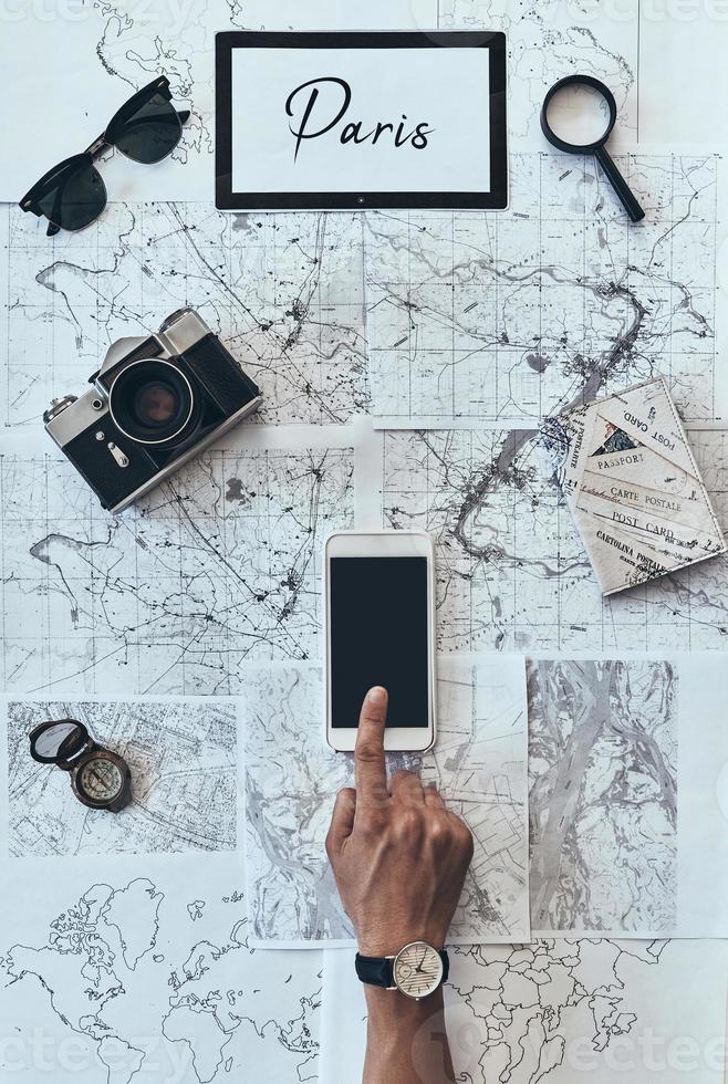 Planning new destination. Close up top view of man using smart phone in front of the map photo