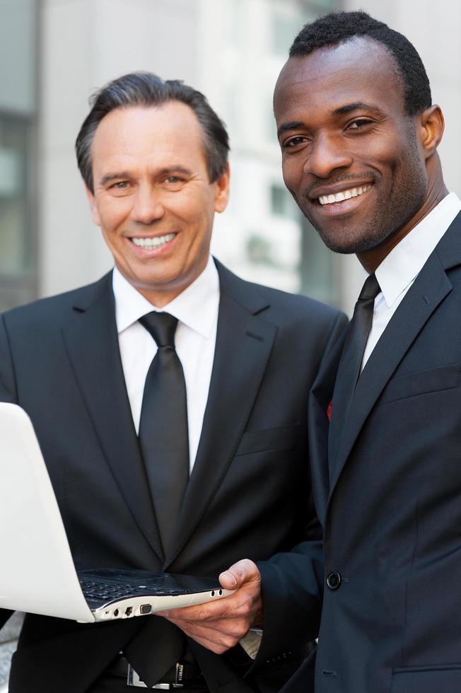 Business discussion. Two confident business men looking at laptop while one of them pointing it with finger photo