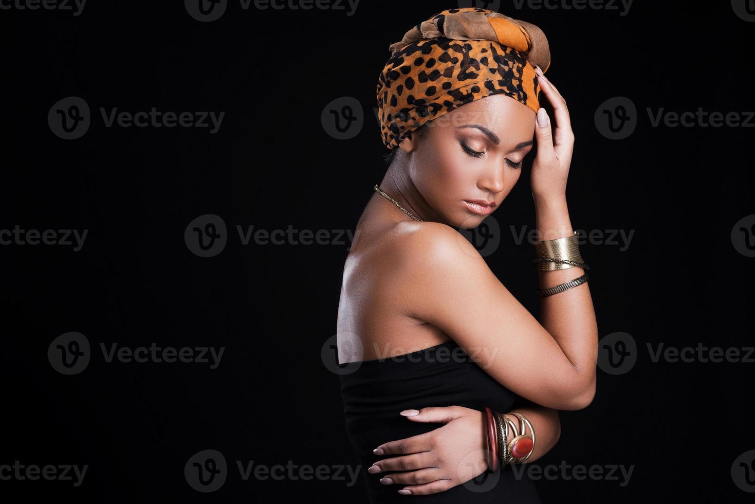 verdadera belleza africana. hermosa mujer africana con un pañuelo en la cabeza y posando sobre fondo negro foto