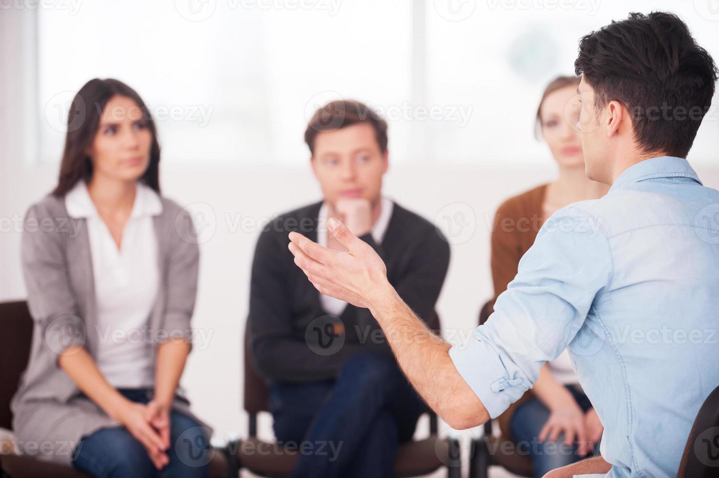 compartir sus problemas con la gente. vista del hombre diciendo algo y gesticulando mientras un grupo de personas sentadas frente a él y escuchando foto