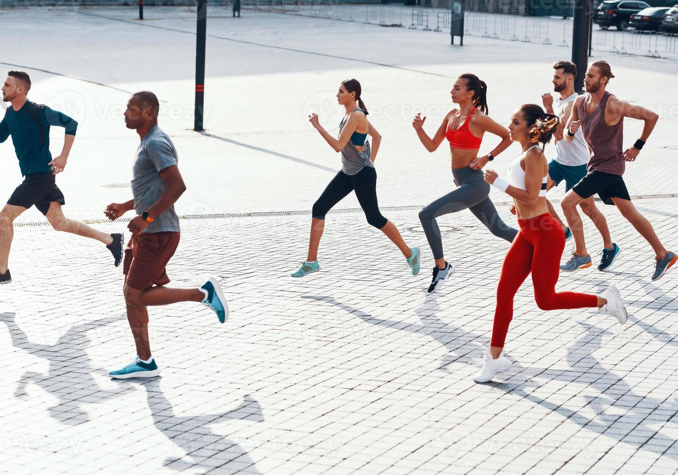 vista superior completa de personas con ropa deportiva trotando mientras hacen ejercicio en la acera al aire libre foto