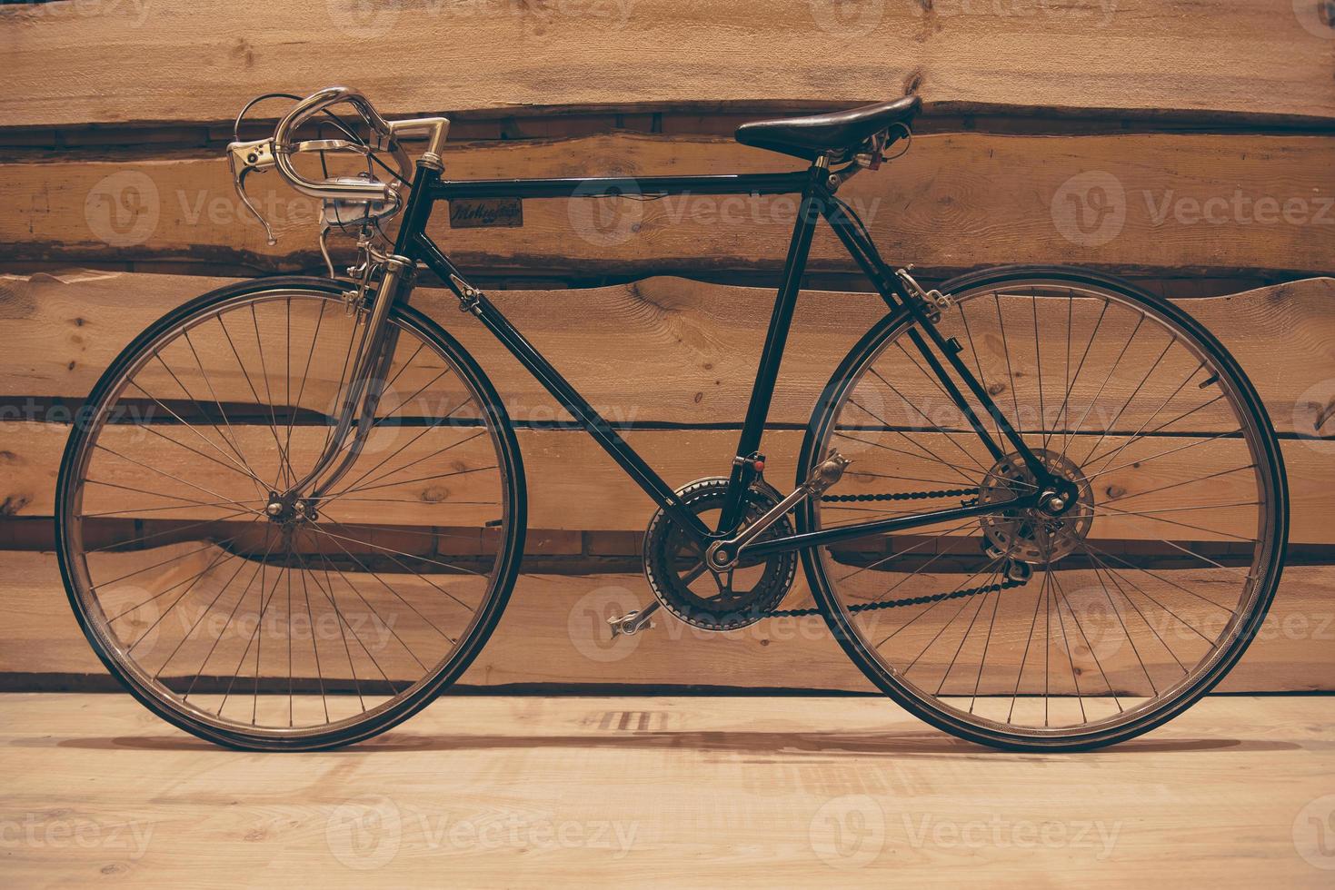 Retro styled bicycle. Close-up of retro styled bicycle standing against rough wooden wall photo