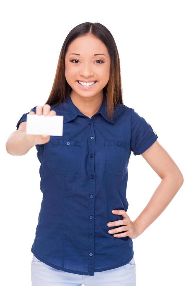 Copy space on her business card. Attractive young Asian woman showing her business card and smiling while standing isolated on white photo