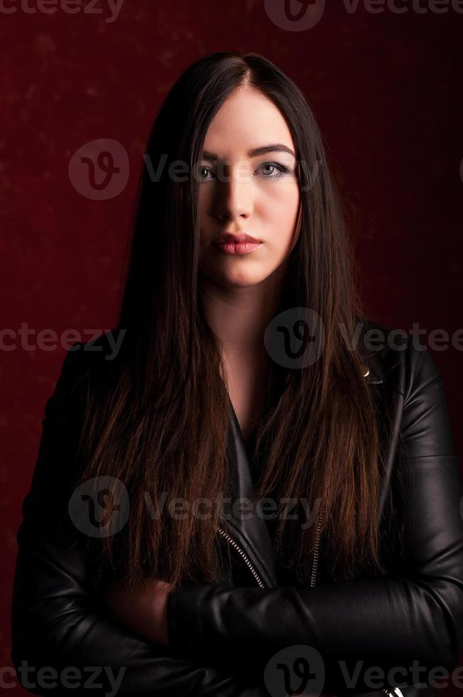 Confident beauty. Beautiful young woman in black jacket looking at camera and holding her arms crossed photo