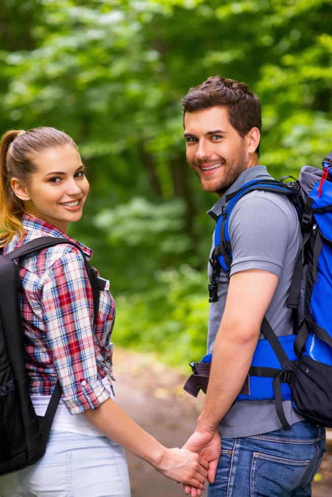 Couple traveling with backpacks. Happy young loving couple carrying backpacks and looking over