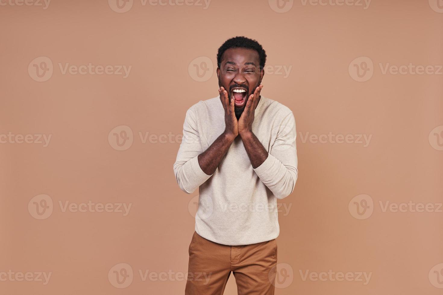 Handsome young African man in casual closing smiling and looking at camera photo