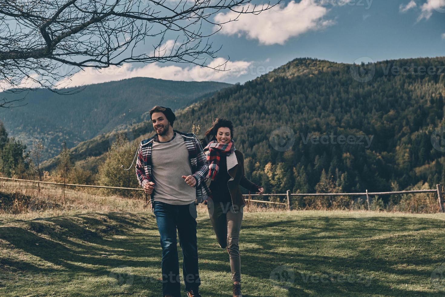 Two hearts full of love. Happy young couple smiling while running on the valley in mountains outdoors photo