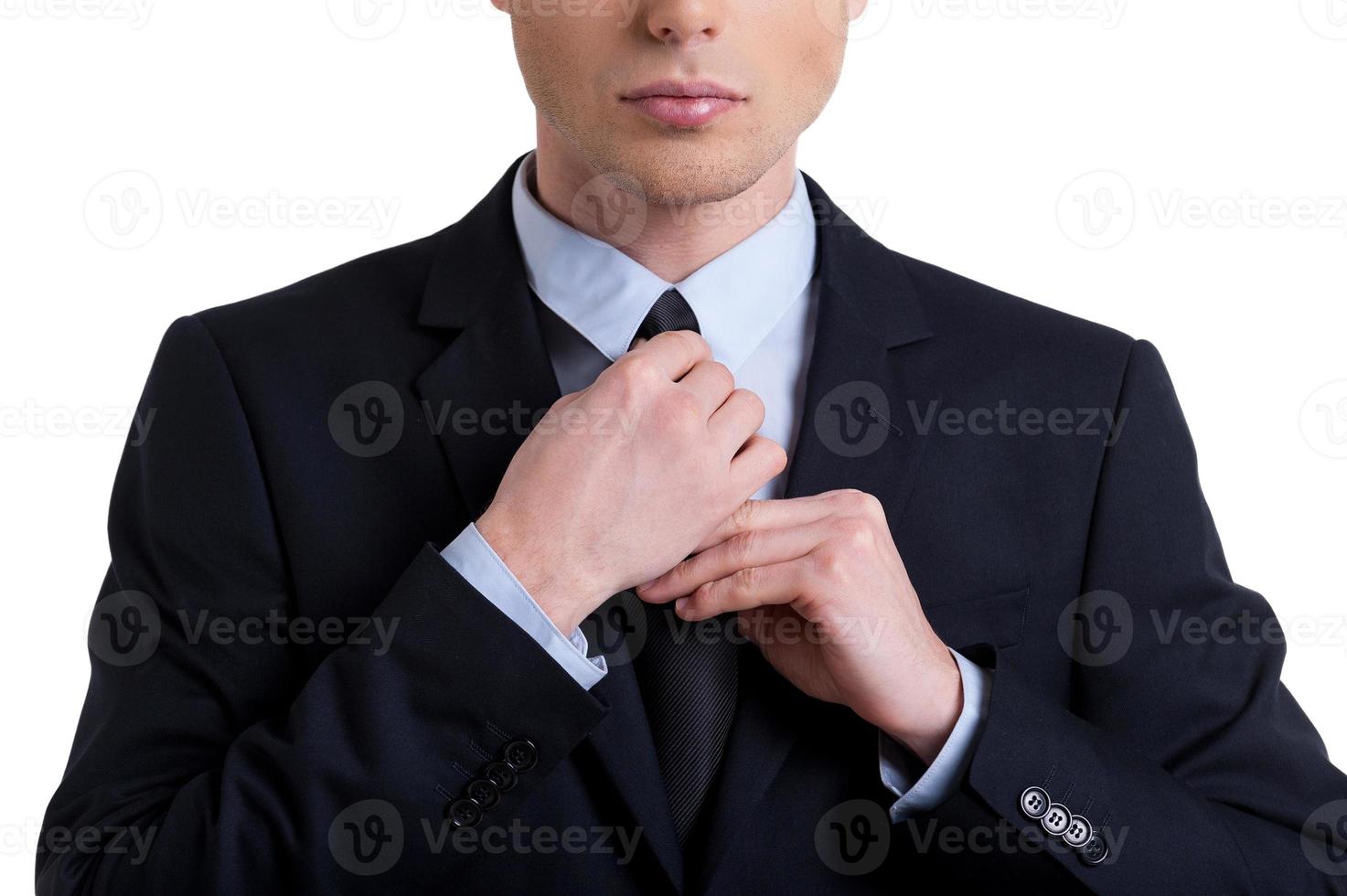 I am ready  Cropped image of confident young man in formalwear adjusting his necktie while standing isolated on white photo