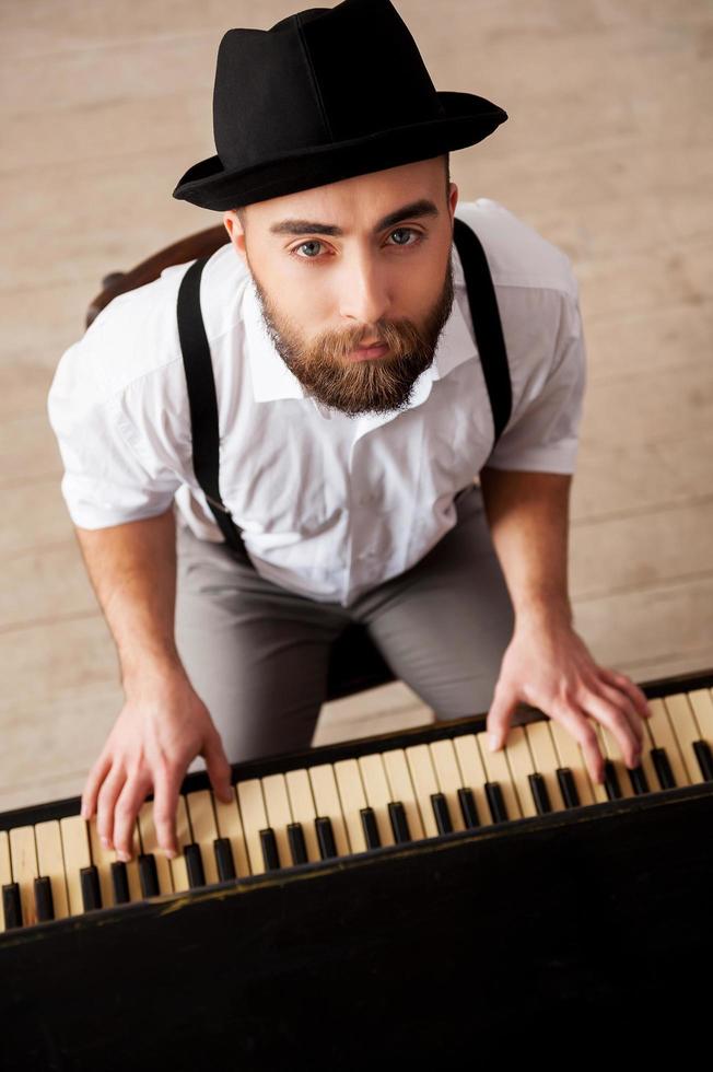 expresarme con la música. vista superior de guapos jóvenes barbudos tocando el piano y mirando a la cámara foto