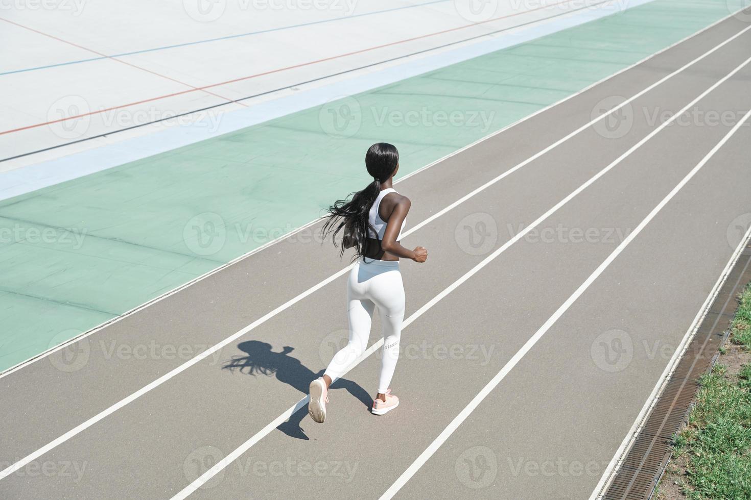 vista superior de una hermosa joven africana con ropa deportiva corriendo en la pista al aire libre foto