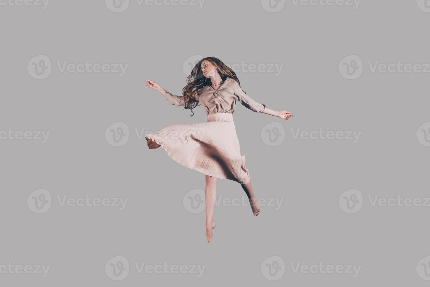 belleza flotante. foto de estudio de una atractiva joven vestida flotando en el aire