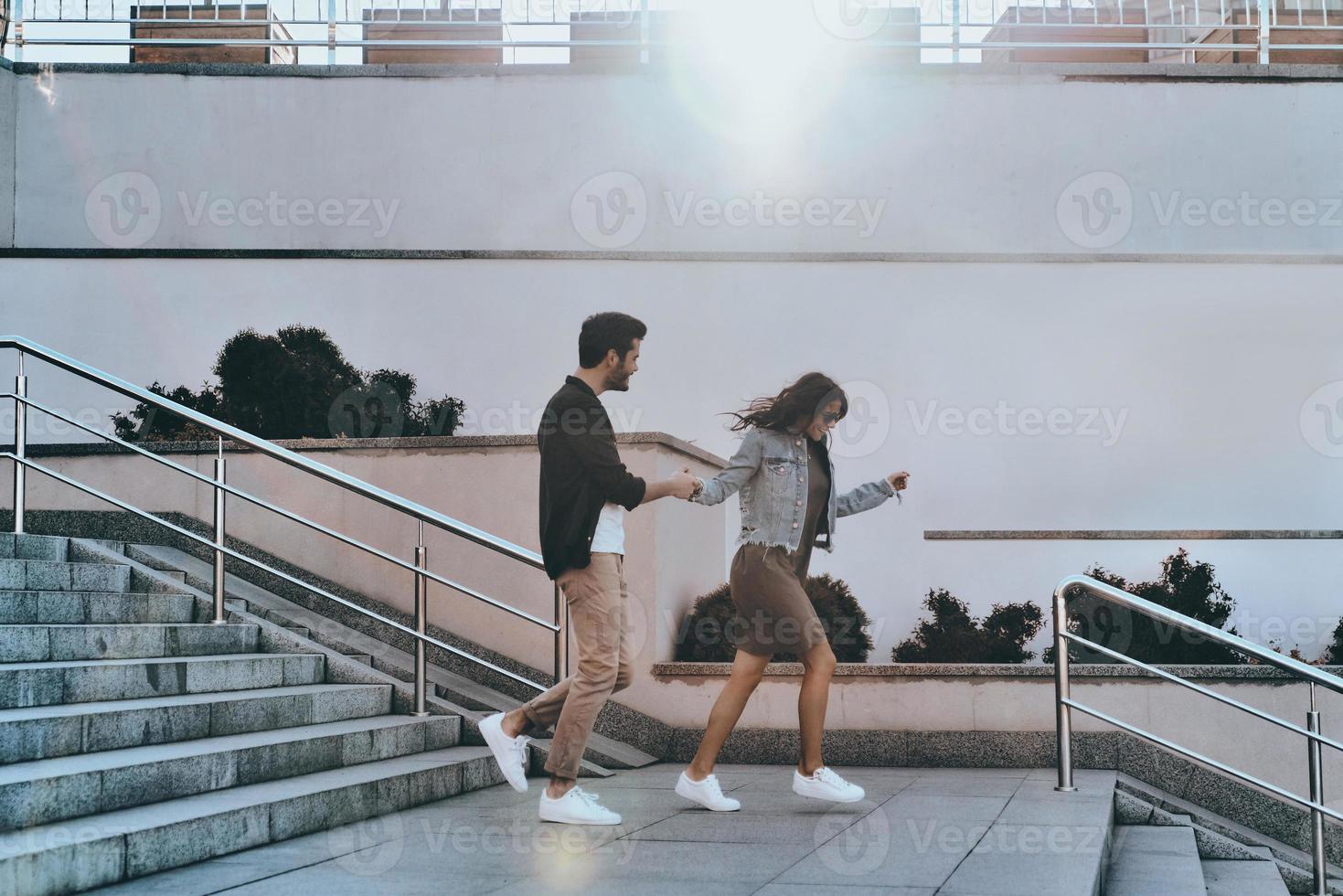 He will never let her go. Full length of handsome man and young attractive woman holding hands while walking down the stairs outdoors photo