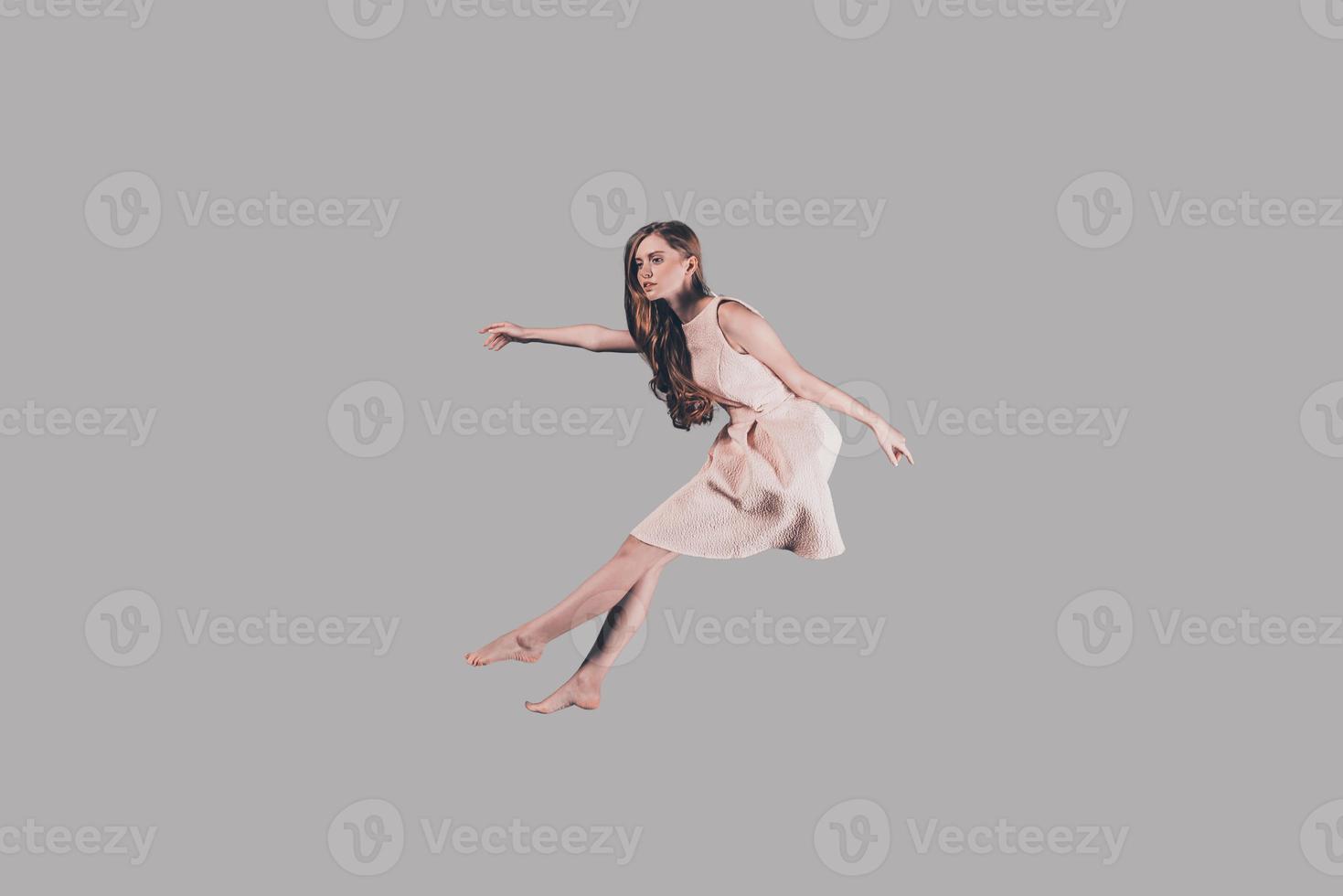 Hovering beauty. Studio shot of attractive young woman hovering in air photo