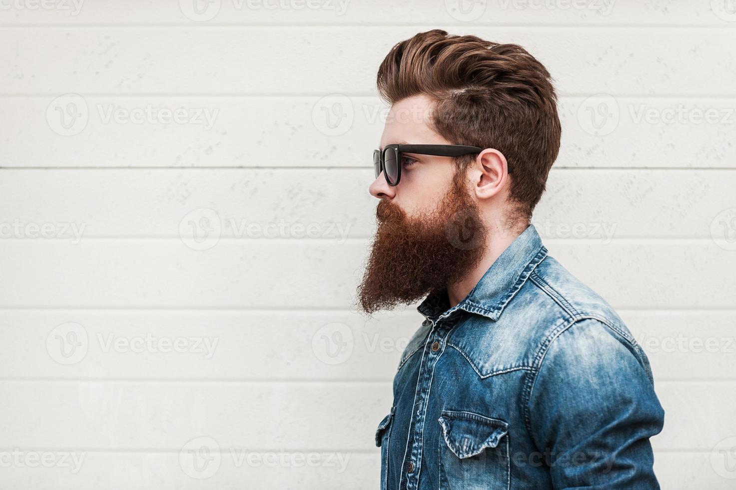 Perfect style. Side view of young bearded man in eyewear looking away while standing outdoors photo