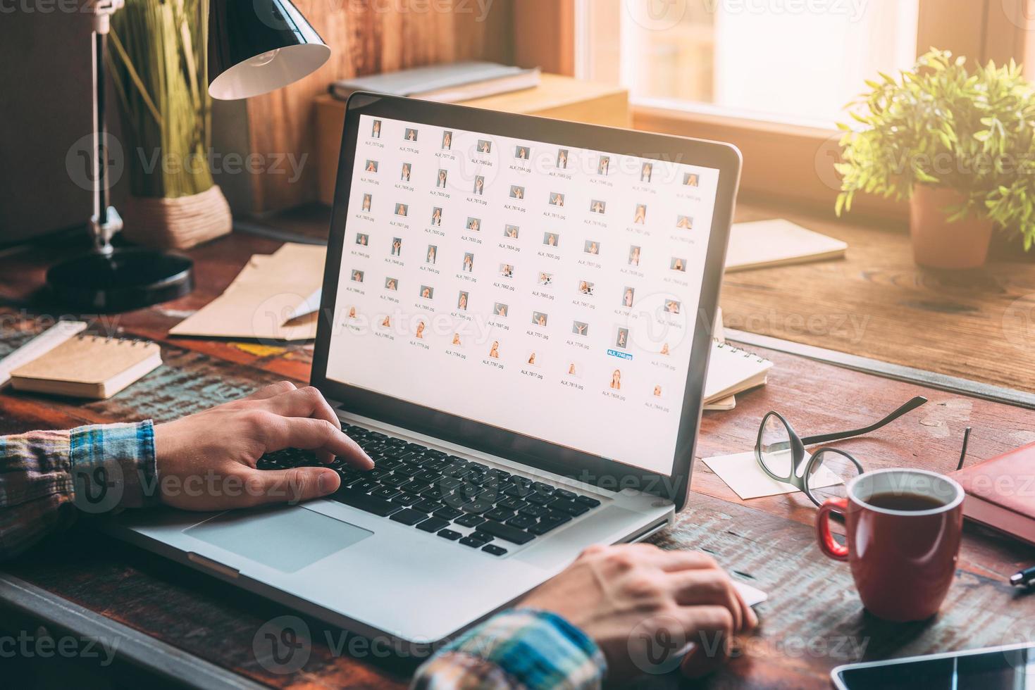 Working at home. Close-up image of man working on laptop with copy space while sitting at the rustic wooden table photo