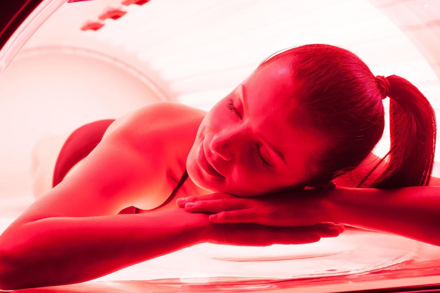 Woman on tanning bed. Attractive young woman lying on tanning bed and keeping eyes closed photo