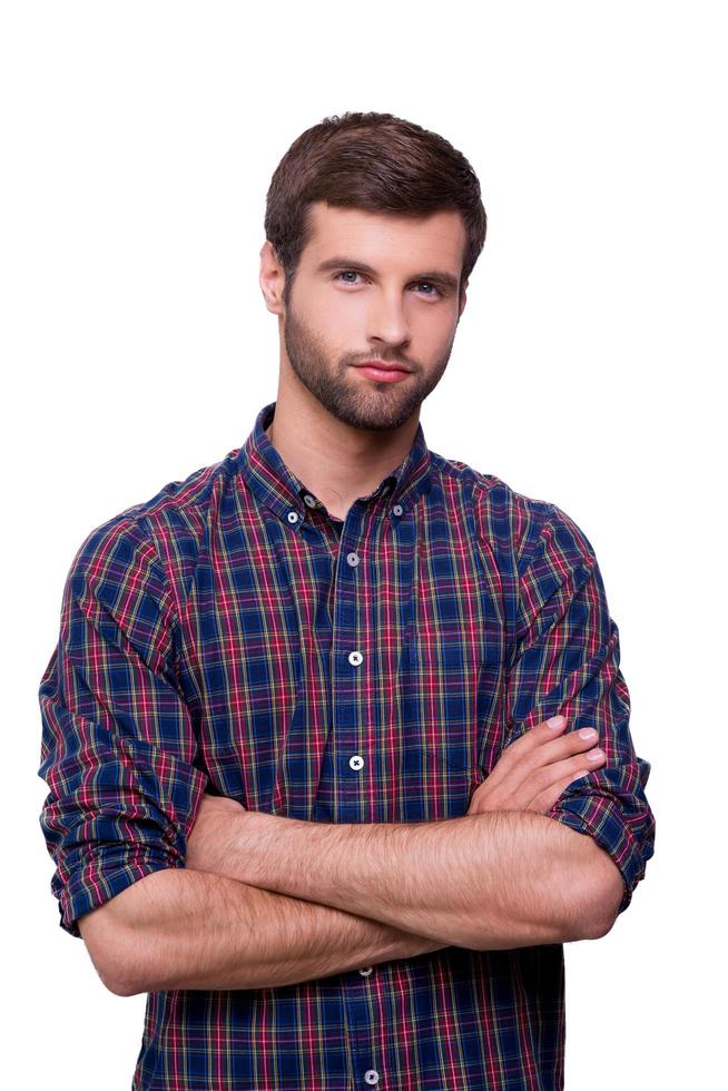 Casually handsome. Portrait of handsome young man in casual shirt keeping arms crossed and looking at camera while standing isolated on white photo