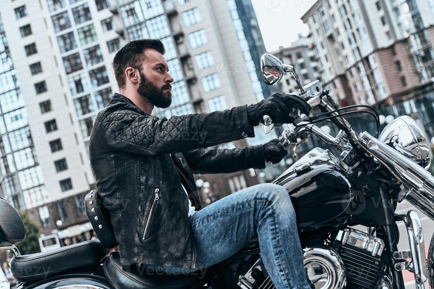 Just him and the road. Handsome young man sitting on the motorbike while spending time outdoors photo