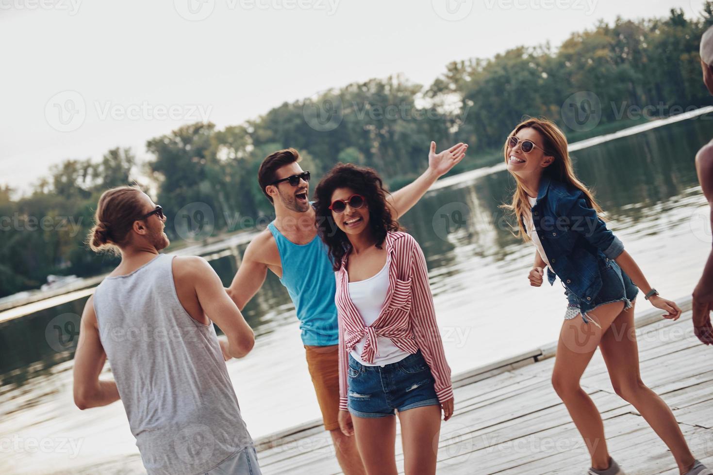 Having fun together. Group of young people in casual wear smiling and having fun while standing on the pier photo