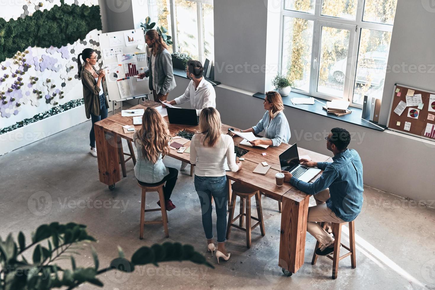 Discussing risky ideas. Top view of two modern young colleagues conducting a business presentation while standing in the board room photo