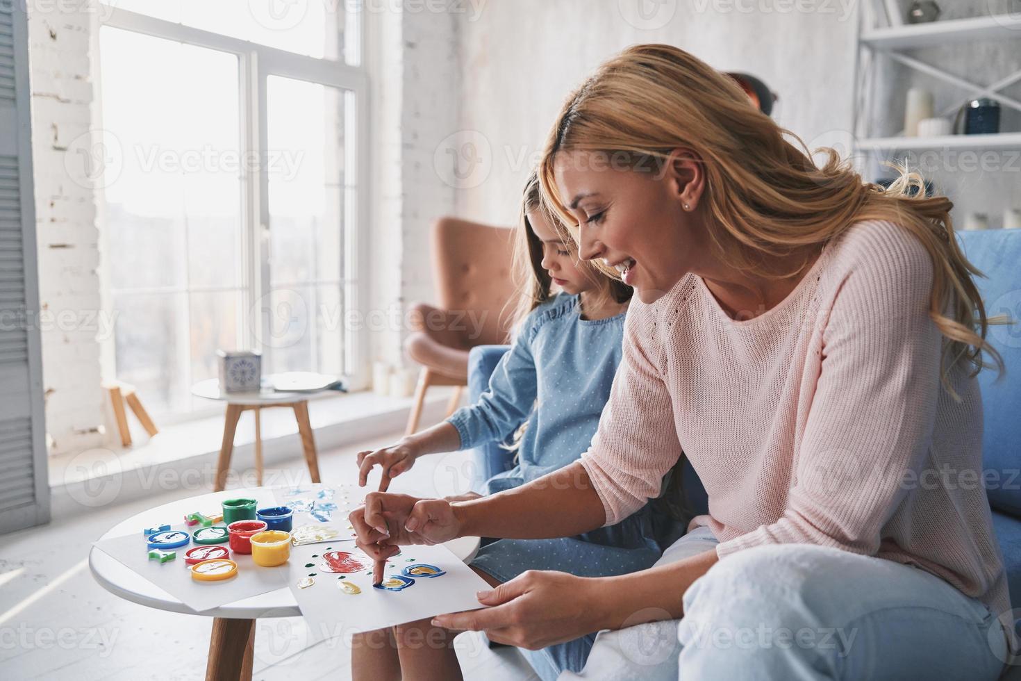 actividad favorita. madre e hija pintando con los dedos y sonriendo mientras pasan tiempo en casa foto