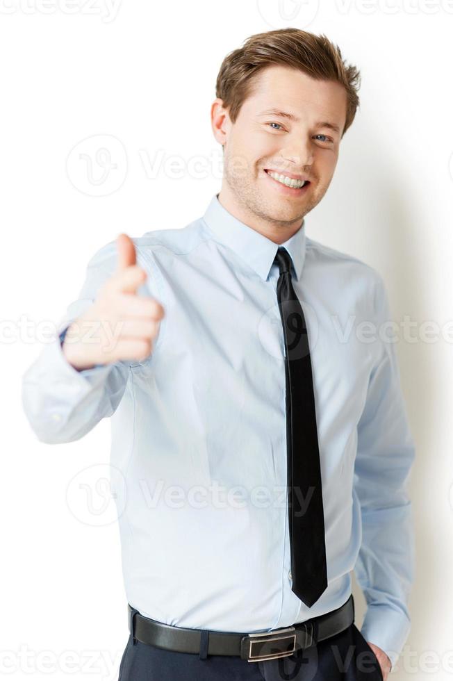 Te elijo a ti, un apuesto joven con camisa y corbata señalándote y sonriendo mientras estás aislado en blanco foto