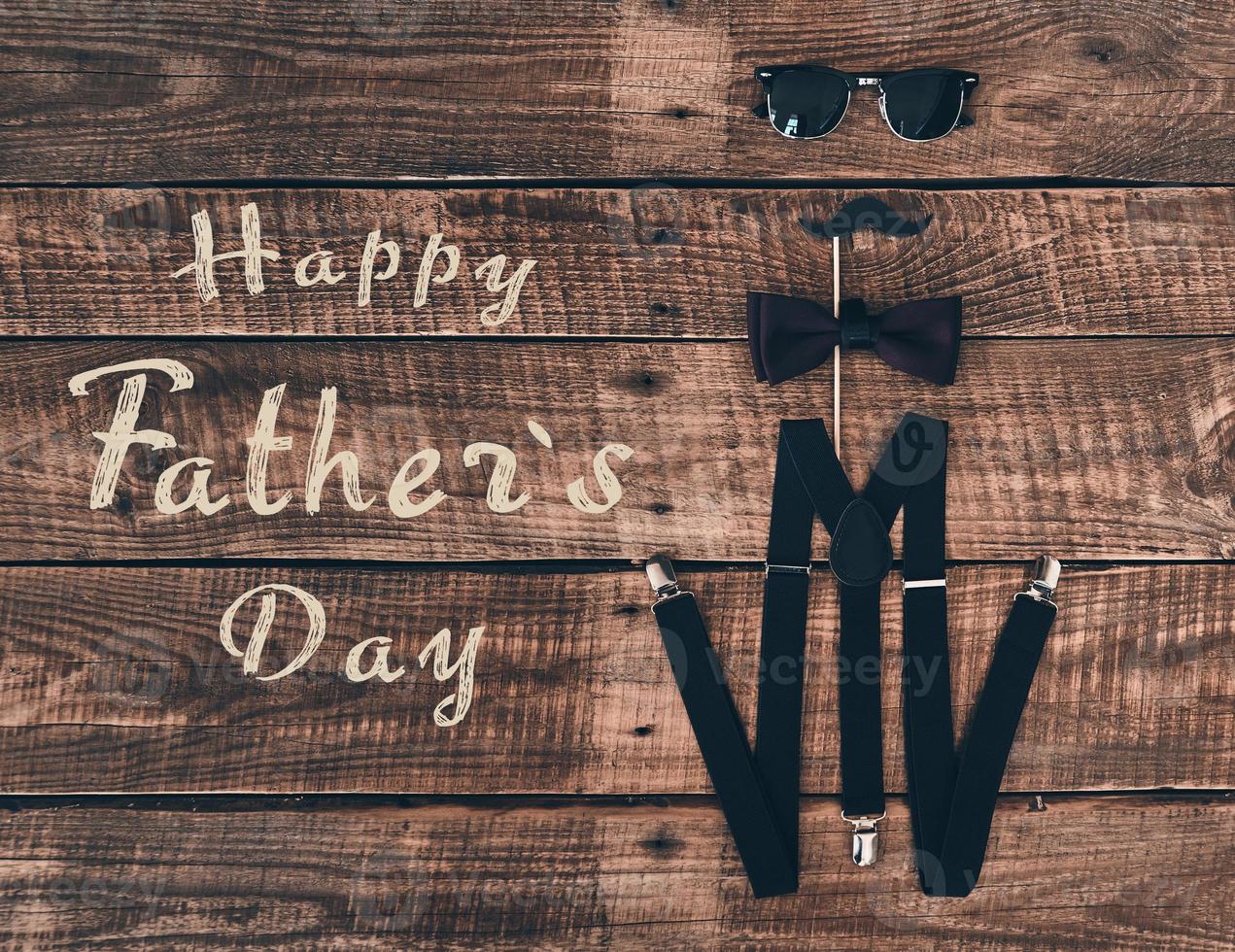 Father's day. High angle shot of suspenders, prop, bow tie and eyewear lying on wooden desk photo