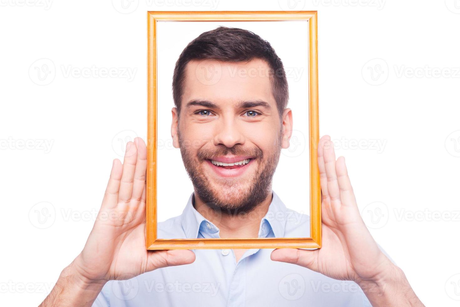 Portrait of me Handsome young man in shirt looking at camera through picture frame while standing against white background photo