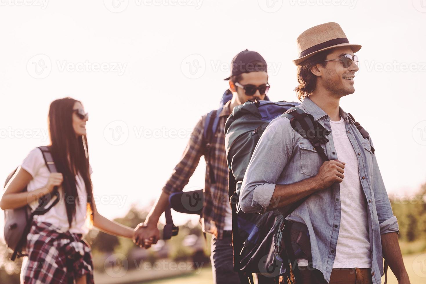 Summer hike with friends. Young people with backpacks walking together and looking happy photo